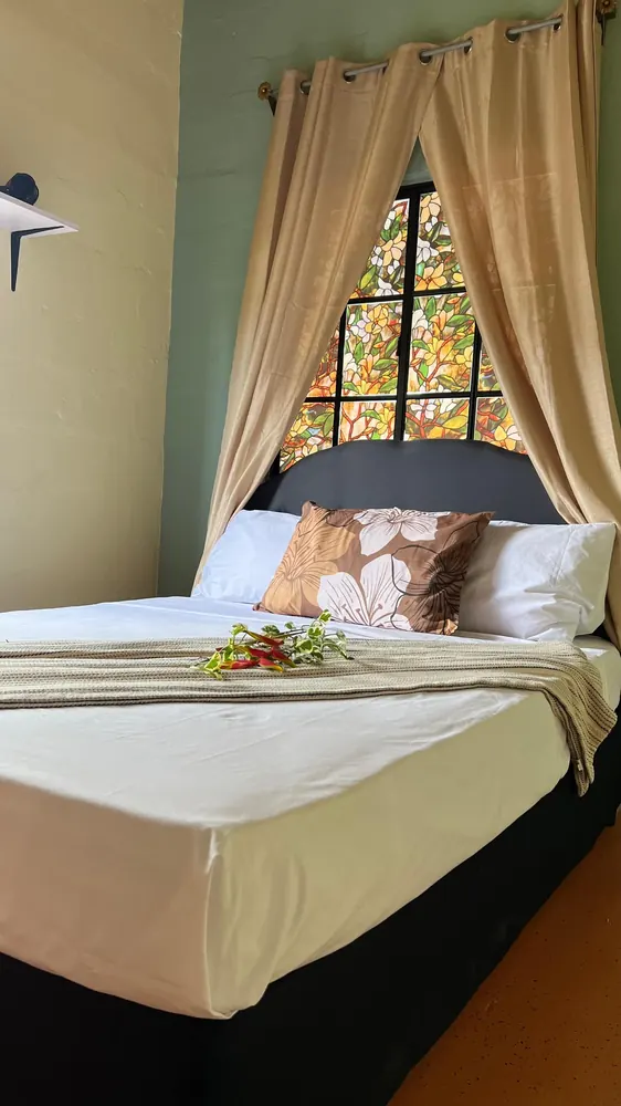 A closer view of the bed, cushions and softly draped bedroom window.
