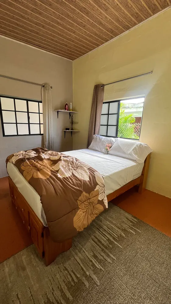 The second bedroom with a floral duvet, two windows and a timber ceiling.